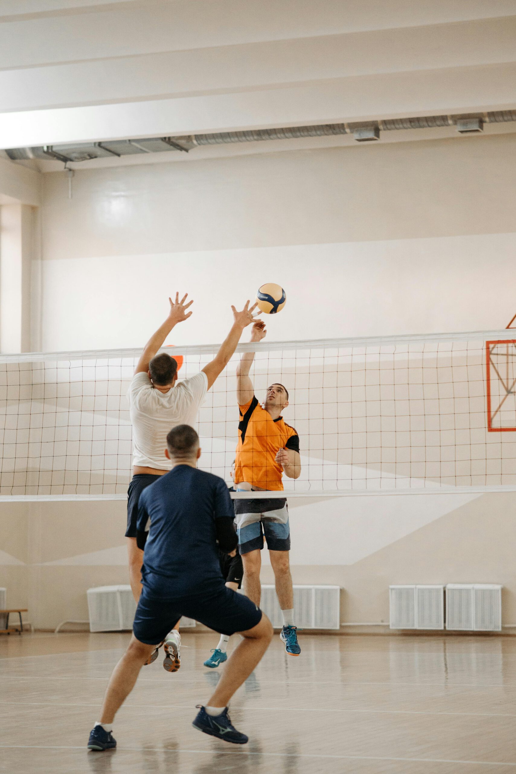 Three male athletes playing volleyball indoors, capturing action and sport intensity.